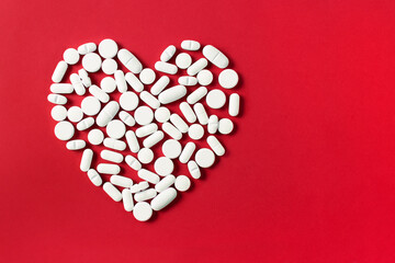 heart shaped pills on red background	