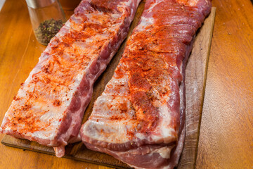Raw pork ribs pieces sprinkled with spices, fragment close-up
