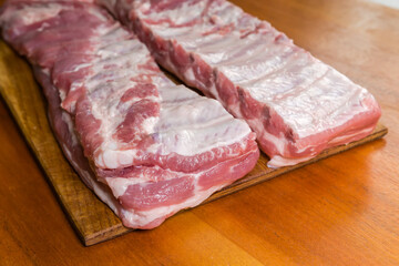 Raw pork ribs pieces on wooden cutting board close-up