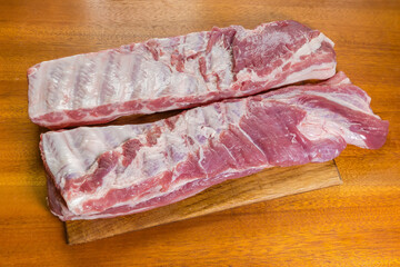 Two pieces of raw pork ribs on wooden cutting board