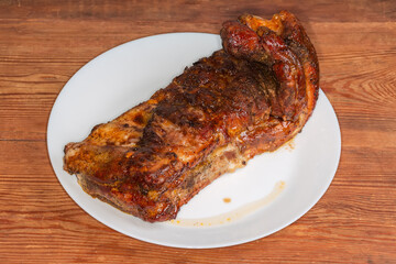 Piece of baked pork ribs on plate on rustic table
