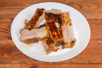 Sliced baked pork ribs on plate on a rustic table
