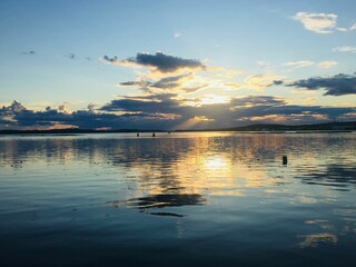 Naklejka premium Sunset over a lake with clouds reflecting from water