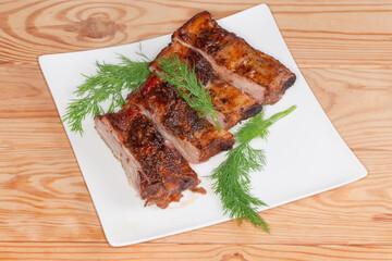 Sliced baked pork ribs portion on plate on rustic table