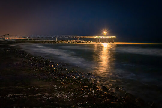 pantalan en la playa de xilxes por la noche con el mar iluminado por la luz de la farola y la playa iluminada por la luz de la luna, Castell&oacute;n, Spain