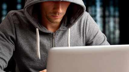 Hacker works on laptop in a dimly lit room with binary code background - Powered by Adobe