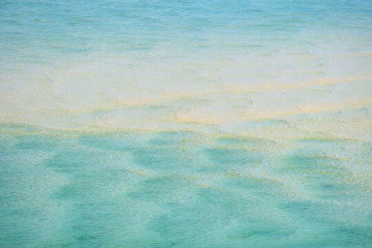 Looking through blue seawater at patterns in the sand