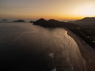 magnificent golden hour sunset on beach with forest mountains