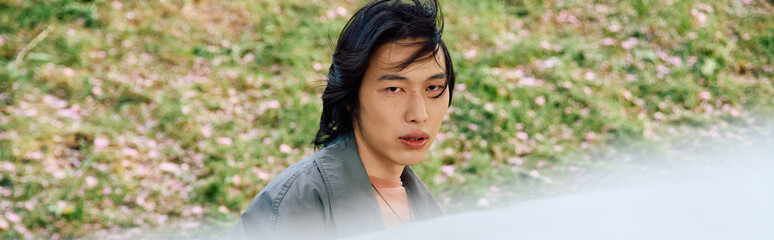 Stylish young man in grey outfit enjoys a serene moment in the park during spring season