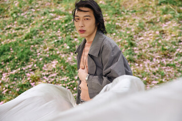 Stylish young man embraces nature in a trendy grey outfit at a serene park setting