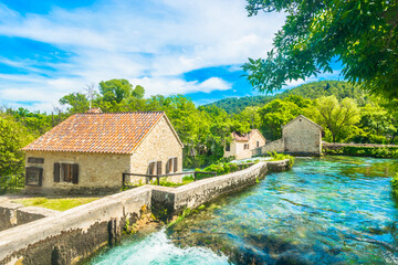 Scenic view of traditional stone houses and historic watermills within Krka National Park, Dalmatia, Croatia, surrounded by lush greenery and flowing streams, forming  iconic tourist attraction