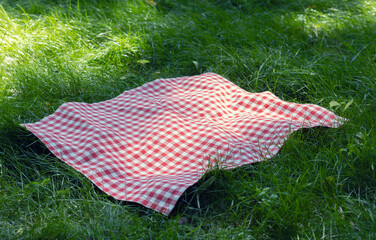 Red checkered picnic towel plaid on grass, tablecloth outdoors.Food advertisement template.