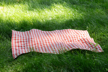 Picnic cloth on grass empty copy space food afvertisement background. Tablecloth plaid on lawn outdoors.