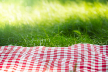 Red checkered picnic towel plaid on grass, tablecloth outdoors.Food advertisement summer template.