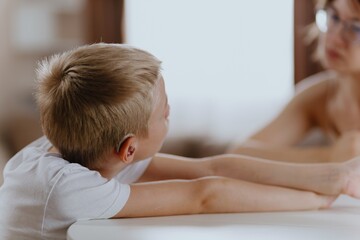 Young mother helps her hard-of-hearing son with schoolwork at home. A natural, heartfelt moment of...