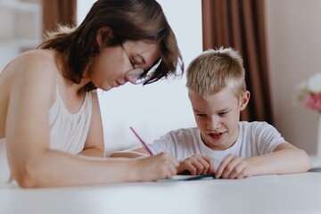 Young mother helps her hard-of-hearing son with schoolwork at home. A natural, heartfelt moment of...