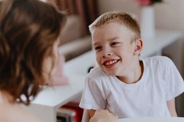 Young mother helps her hard-of-hearing son with schoolwork at home. A natural, heartfelt moment of...