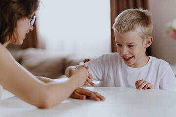 Young mother helps her hard-of-hearing son with schoolwork at home. A natural, heartfelt moment of...