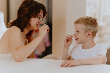 Young mother helps her hard-of-hearing son with schoolwork at home. A natural, heartfelt moment of...