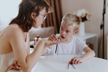 Young mother helps her hard-of-hearing son with schoolwork at home. A natural, heartfelt moment of...