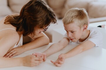 Young mother helps her hard-of-hearing son with schoolwork at home. A natural, heartfelt moment of...