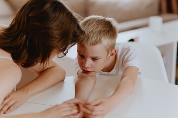 Young mother helps her hard-of-hearing son with schoolwork at home. A natural, heartfelt moment of...
