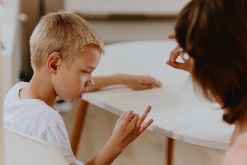 Young mother helps her hard-of-hearing son with schoolwork at home. A natural, heartfelt moment of...