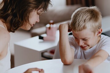 Young mother helps her hard-of-hearing son with schoolwork at home. A natural, heartfelt moment of...