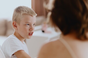 Young mother helps her hard-of-hearing son with schoolwork at home. A natural, heartfelt moment of...