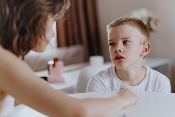 Young mother helps her hard-of-hearing son with schoolwork at home. A natural, heartfelt moment of...