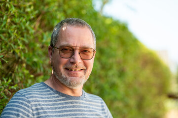 Portrait of a 49 yo man with glasses and a beard against a green background in Ternat, Flemish Brabant, Belgium