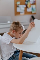 Young mother helps her hard-of-hearing son with schoolwork at home. A natural, heartfelt moment of...