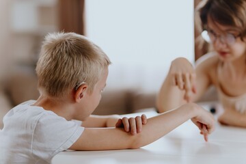Young mother helps her hard-of-hearing son with schoolwork at home. A natural, heartfelt moment of...