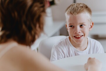 Young mother helps her hard-of-hearing son with schoolwork at home. A natural, heartfelt moment of...
