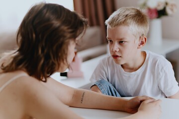 Young mother helps her hard-of-hearing son with schoolwork at home. A natural, heartfelt moment of...