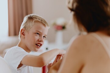 Young mother helps her hard-of-hearing son with schoolwork at home. A natural, heartfelt moment of...