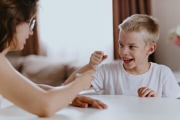 Young mother helps her hard-of-hearing son with schoolwork at home. A natural, heartfelt moment of...
