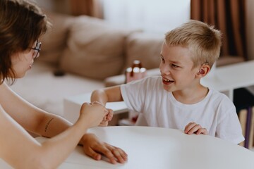 Young mother helps her hard-of-hearing son with schoolwork at home. A natural, heartfelt moment of...