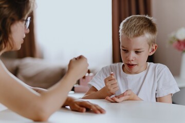 Young mother helps her hard-of-hearing son with schoolwork at home. A natural, heartfelt moment of...