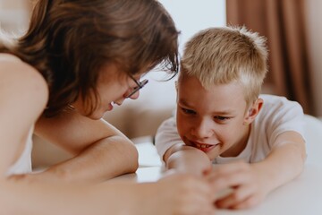 Young mother helps her hard-of-hearing son with schoolwork at home. A natural, heartfelt moment of...
