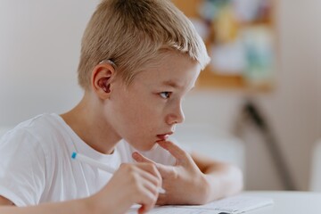 Young mother helps her hard-of-hearing son with schoolwork at home. A natural, heartfelt moment of...