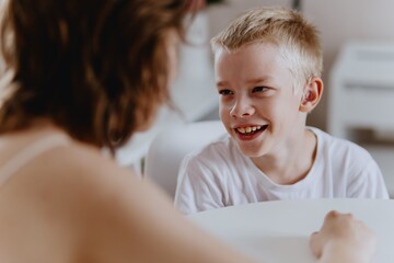 Young mother helps her hard-of-hearing son with schoolwork at home. A natural, heartfelt moment of...