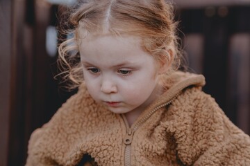 Beautiful 3-year-old girl playing on a neighborhood playground swinging, running on the grass, and enjoying fresh air. A joyful, natural moment full of real emotions and unaltered beauty