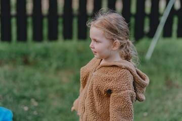 Beautiful 3-year-old girl playing on a neighborhood playground swinging, running on the grass, and enjoying fresh air. A joyful, natural moment full of real emotions and unaltered beauty
