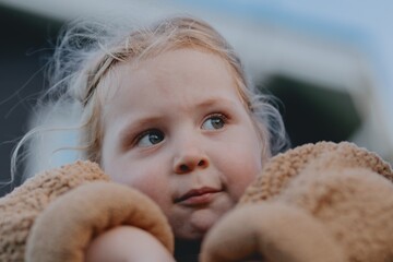 Beautiful 3-year-old girl playing on a neighborhood playground swinging, running on the grass, and enjoying fresh air. A joyful, natural moment full of real emotions and unaltered beauty