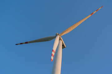 Modern wind turbine against clear blue sky – symbol of clean, renewable energy and sustainable...
