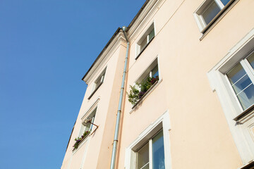 Bright day over a pastel colored building with plants