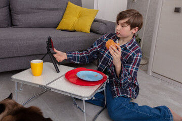 Young boy enjoying snack while recording video at home