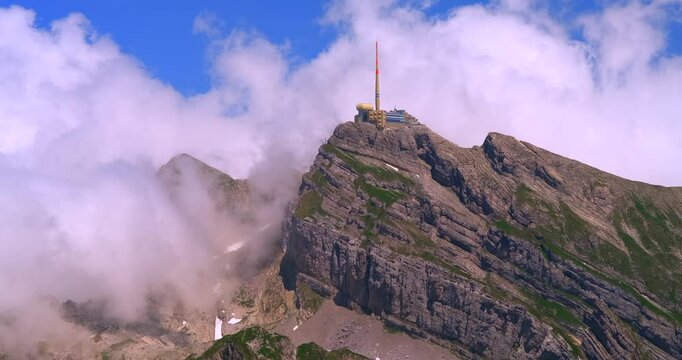 Breathtaking view from a mountain peak with clouds surrounding a summit structure