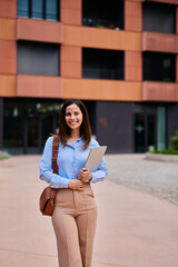 Confident Professional Woman Holding Laptop Outside Modern Urban Building